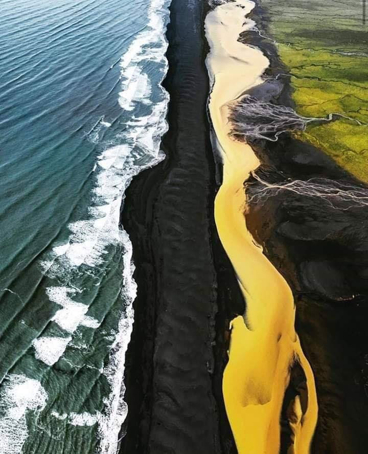 Campi verdi, fiume giallo, spiaggia nera e mare blu: Islanda. Sembra un quadro dipinto. Che spettacolo