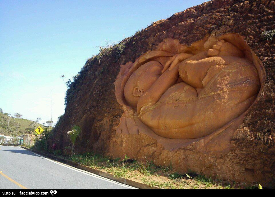 Scultura del neonato nel grembo, sulla parete di roccia