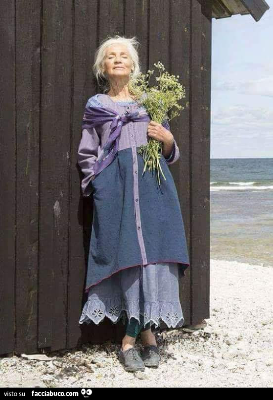 Anziana serena al mare con fiori